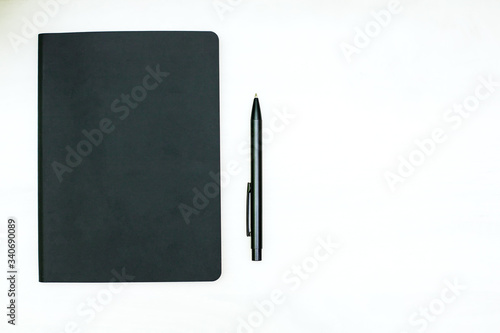 a black diary and a black ballpoint pen lie on a white background