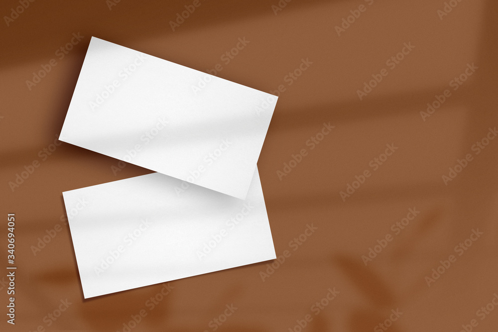 Clean minimal white business card mockup with window shadow on brown color background. Clean minimal white business card mockup with window shadow on brown color background.
