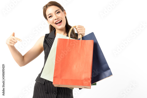 Portrait of young beautiful asian girl wearing black dress holding shopping bags and smile isolated over white background. Online shopping and black friday concept.