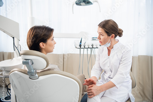 A young woman explaining her dental problem to her doctor  the doctor is listening carefully