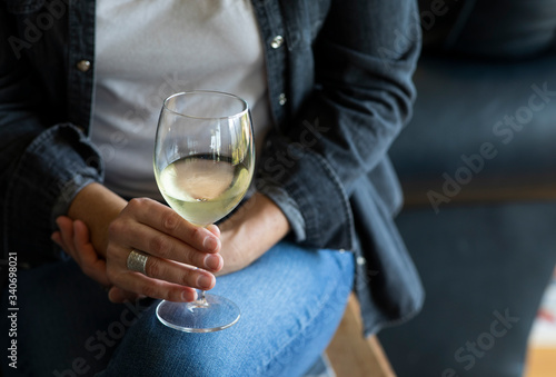 Young woman drinks a glass of white wine alone in her home