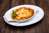 Tasty lasagne with meat covered with cheese served on white plate.