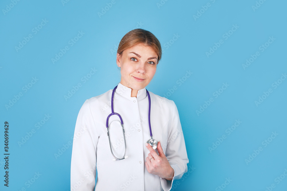 Portrait of an attractive young female doctor in white coat on blue background Portrait of an attractive young female doctor in white coat on blue background