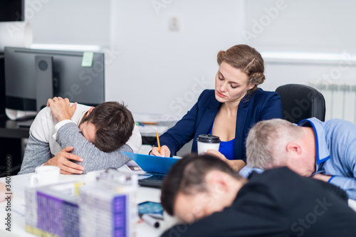 A young business woman working hard, while her colleagues are having a rest in a meeting room
