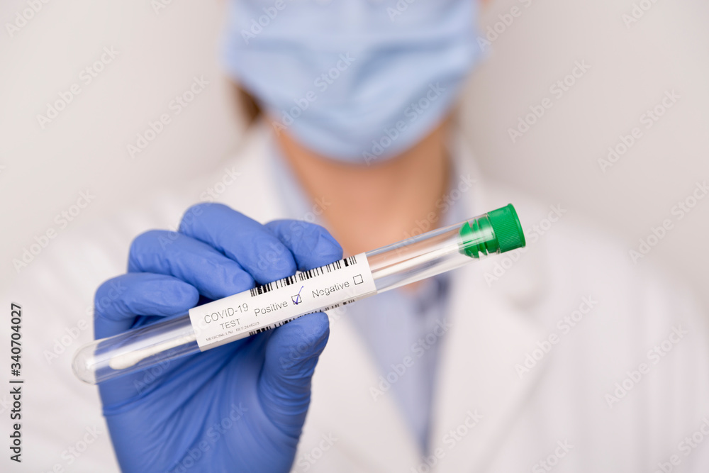 Positive Covid test in the hands of a nurse with blue gloves Positive Covid test in the hands of a nurse with blue gloves