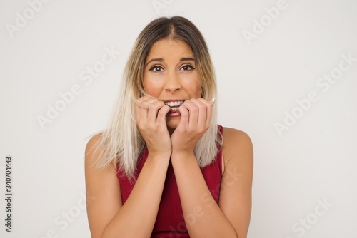 Anxiety - a conceptual image of a beautiful young caucasian woman covering her mouth with her hands and standing outdoors. Scared from something or someone bitting nails.