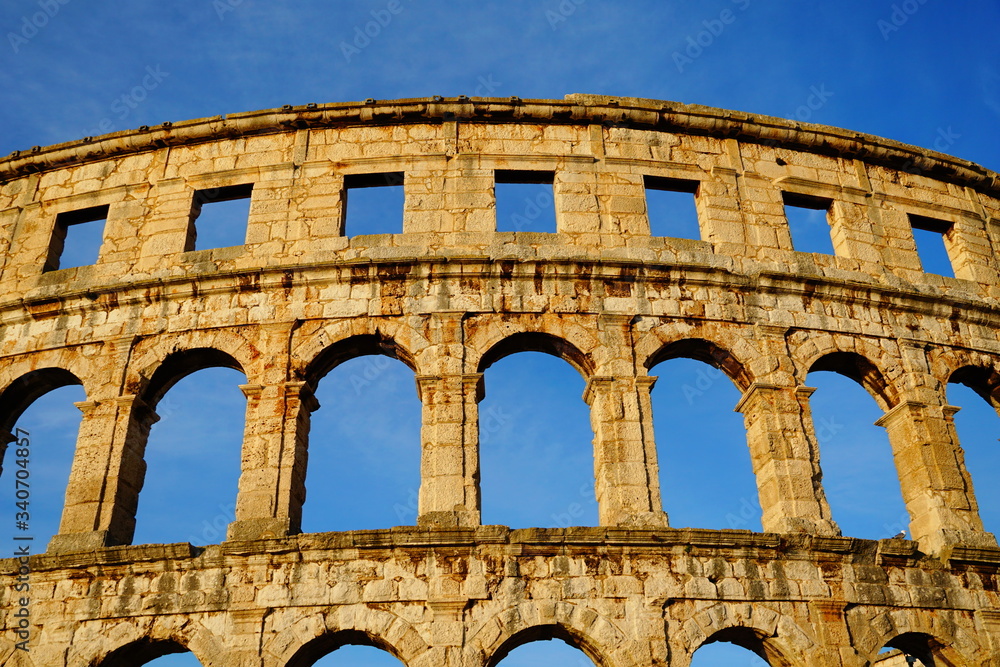 Amazing facade of stone Roman amphitheater through whose window place you can see blue sky