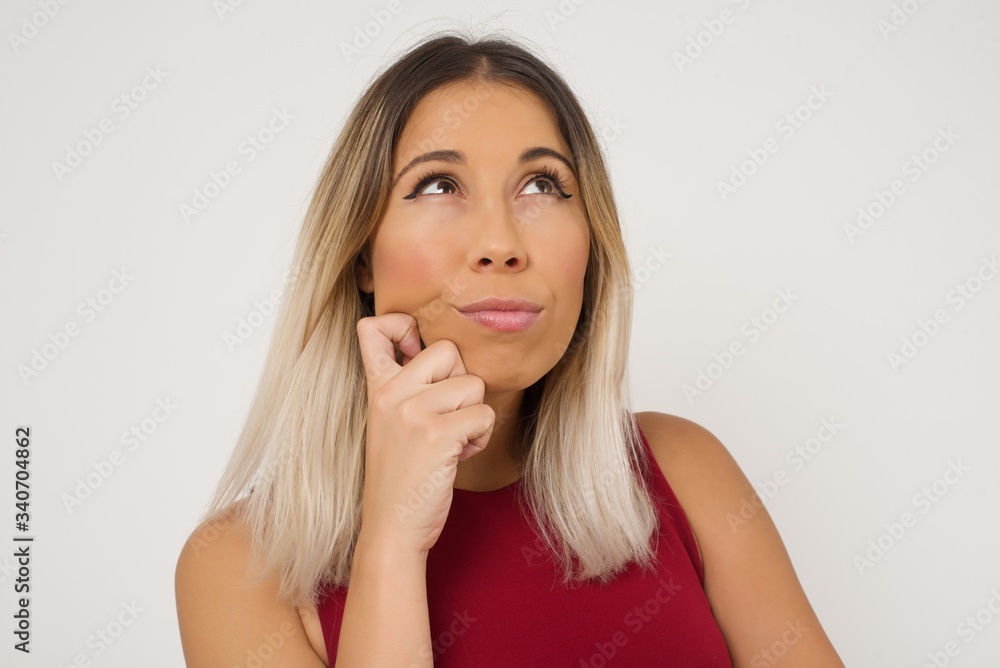 Portrait of thoughtful woman keeps hand under chin, looks away trying to remember something or listens something with interest, dressed casually, poses indoors. Youth concept. Portrait of thoughtful woman keeps hand under chin, looks away trying to remember something or listens something with interest, dressed casually, poses indoors. Youth concept.