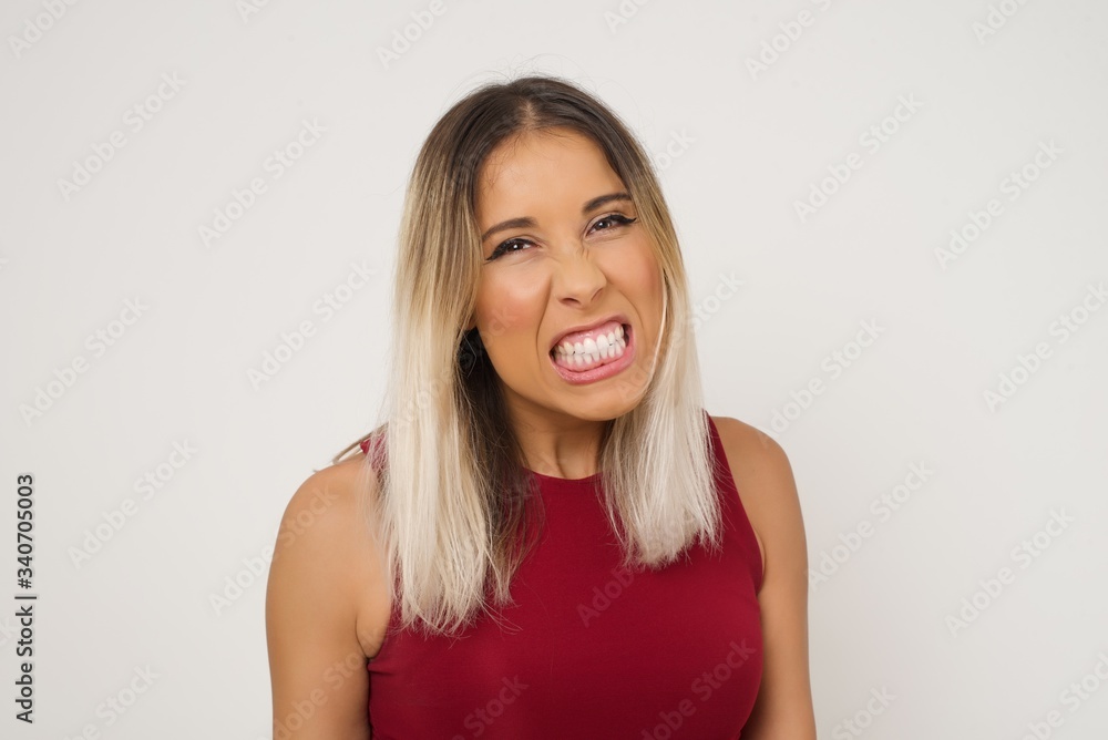Mad crazy woman clenches teeth angrily, being annoyed with coming noise, dressed in fashionable clothes, isolated over gray background. Negative feeling concept. Mad crazy woman clenches teeth angrily, being annoyed with coming noise, dressed in fashionable clothes, isolated over gray background. Negative feeling concept.