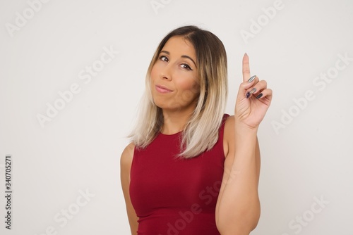 Young caucasian woman standing against gray wall showing and pointing up with fingers number one while smiling confident and happy.