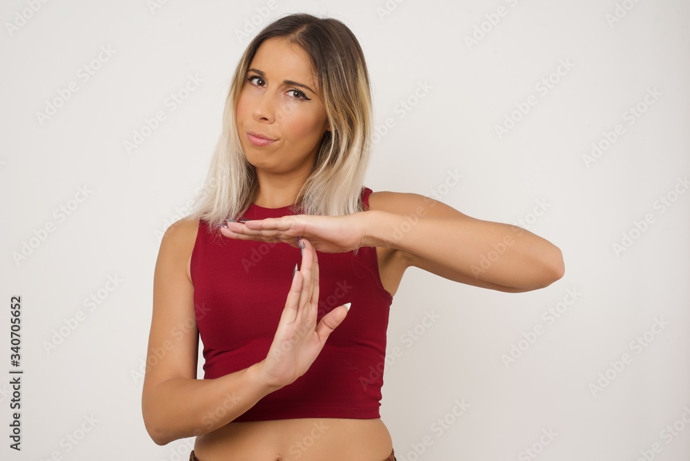 Young pretty blonde girl tired and bored, making a timeout gesture, needs to stop because of work stress, time concept. Standing against gray wall. Young pretty blonde girl tired and bored, making a timeout gesture, needs to stop because of work stress, time concept. Standing against gray wall.