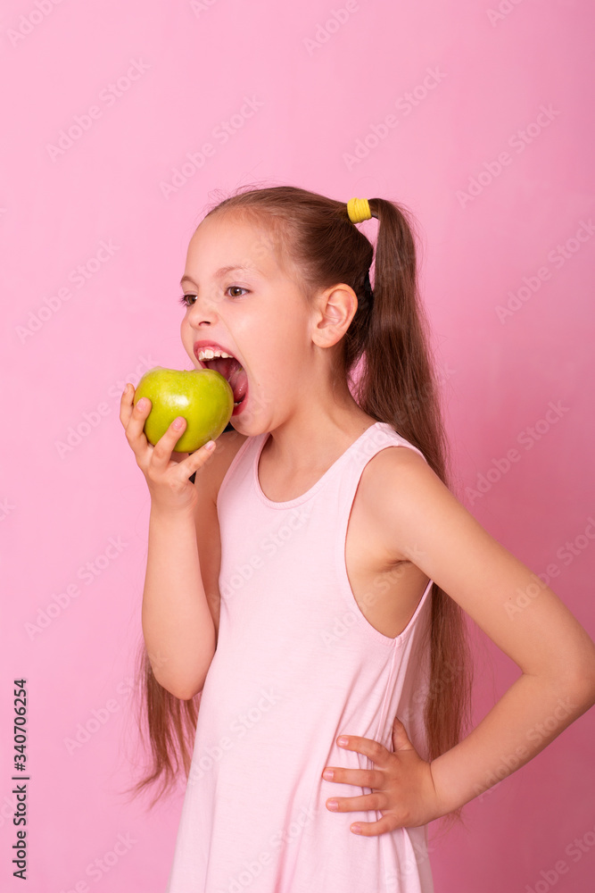 A beautiful portrait of a little girl who eats a green apple. A beautiful portrait of a little girl who eats a green apple.