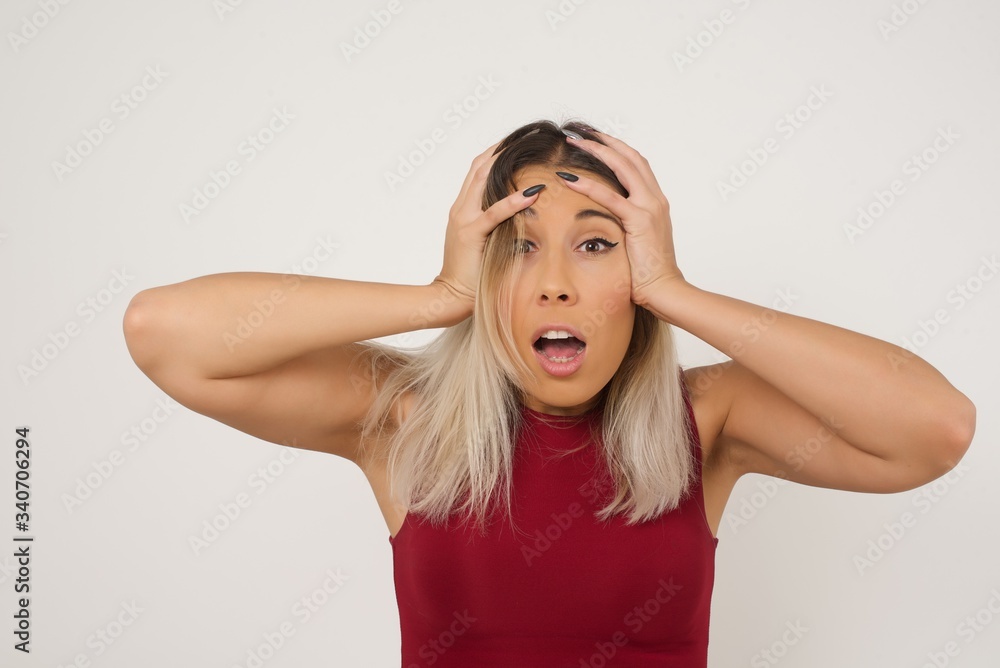 Obraz premium Horrible, stress, shock. Portrait of young emotional crazy woman clasping head in hands. Human emotions, facial expression concept. Trendy colors. Front view