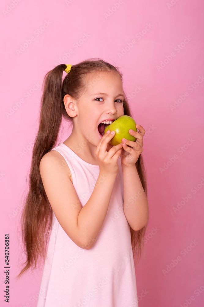 Studio close-up portrait of caucasian girl with funny hairstyle, biting big green apple and looking at camera Studio close-up portrait of caucasian girl with funny hairstyle, biting big green apple and looking at camera