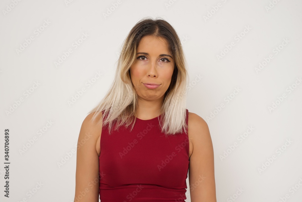 Gloomy, bored girl frowns face looking up, being upset with so much talking hands down, feels tired and wants to leave. Angry sullen woman standing indoors. Gloomy, bored girl frowns face looking up, being upset with so much talking hands down, feels tired and wants to leave. Angry sullen woman standing indoors.