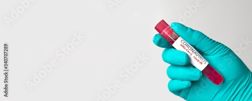 Unrecognizable person holding a red medical injection vaccine coronavirus tube. Panoramic image with copy space.