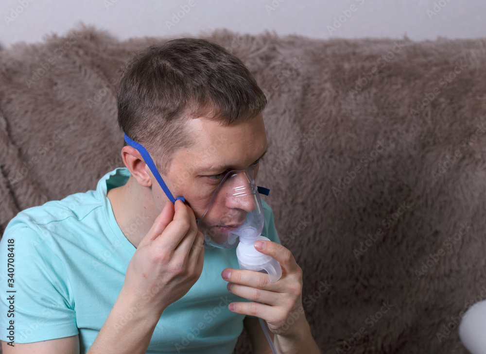 Young caucasian man making inhalation with nebulizer. Treatment of respiratory disease through inhalation of medications