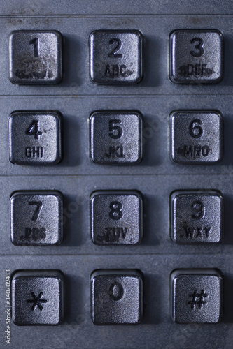 Close up of a dirty public telephone metal keypad. Macro view of the buttons and digits of a public phone keypad.