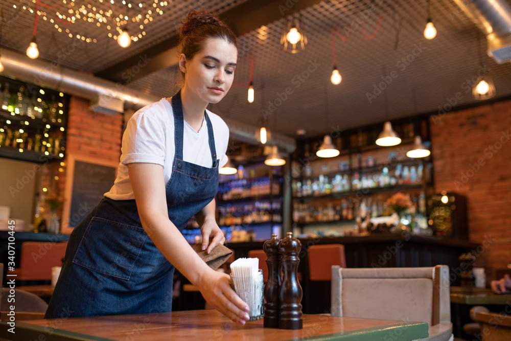 Young waitress of classy restaurant putting glass with bunch of toothpicks