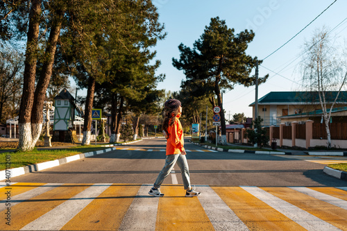 A young woman crosses a pedestrian crossing. Empty road and streets. Side view. Concept of traffic rules © _KUBE_