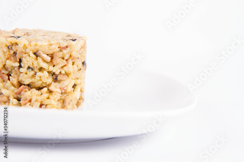 Risotto with button mushroom and bacon on a plate on a white background