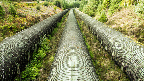 Perspective shot of 3 moss covered water pipelines, Canada