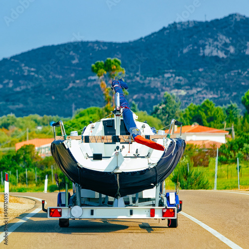 Car with yacht or motor boat on road in Sardinia reflex