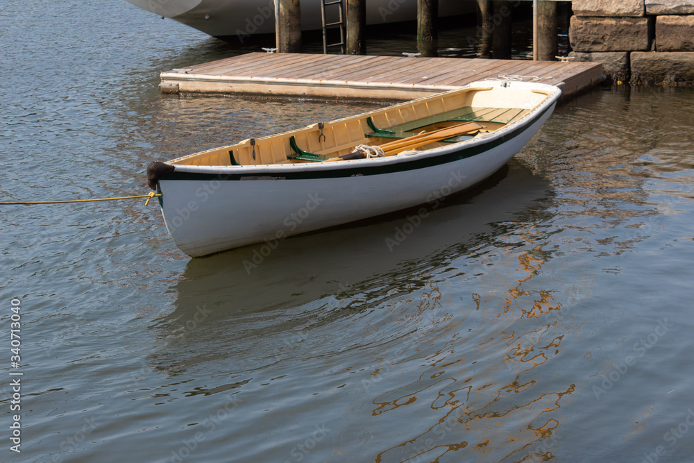 Small white rowboat moored by dock and stone wall, horizontal aspect Small white rowboat moored by dock and stone wall, horizontal aspect