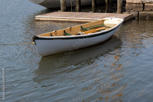 Small white rowboat moored by dock and stone wall, horizontal aspect