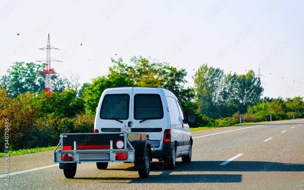 Mini van carrying trailer in asphalt road in Slovenia reflex