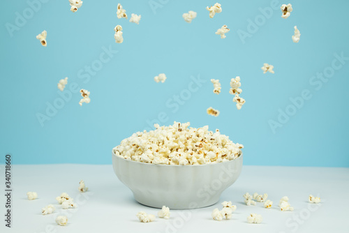 Dreamy image of popcorn falling from the sky over a bowl full of popcorn.