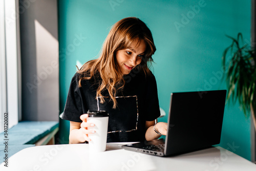 Modern business woman working on smart phone and laptop computer at coffee shop interior
