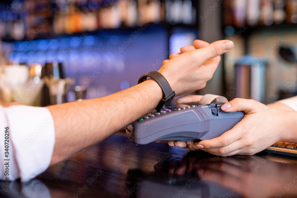 Young client with smartwatch keeping his wrist over payment machine Young client with smartwatch keeping his wrist over payment machine