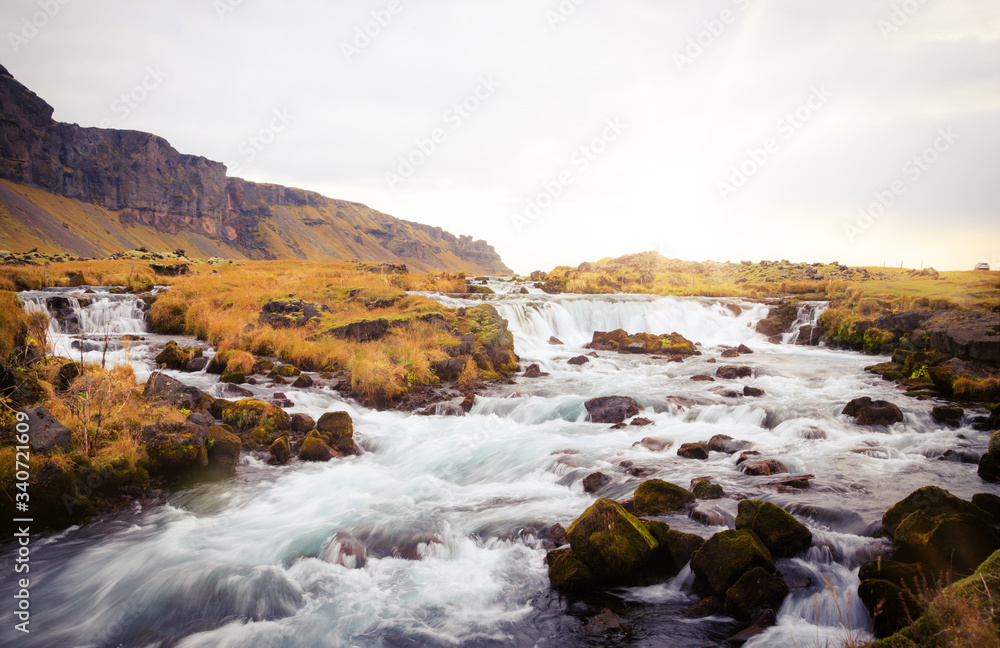Panoramic summer view of small waterfall near Bjodvegur road. Wonderful sunrise on Iceland, Vik location. Beauty of nature concept background..