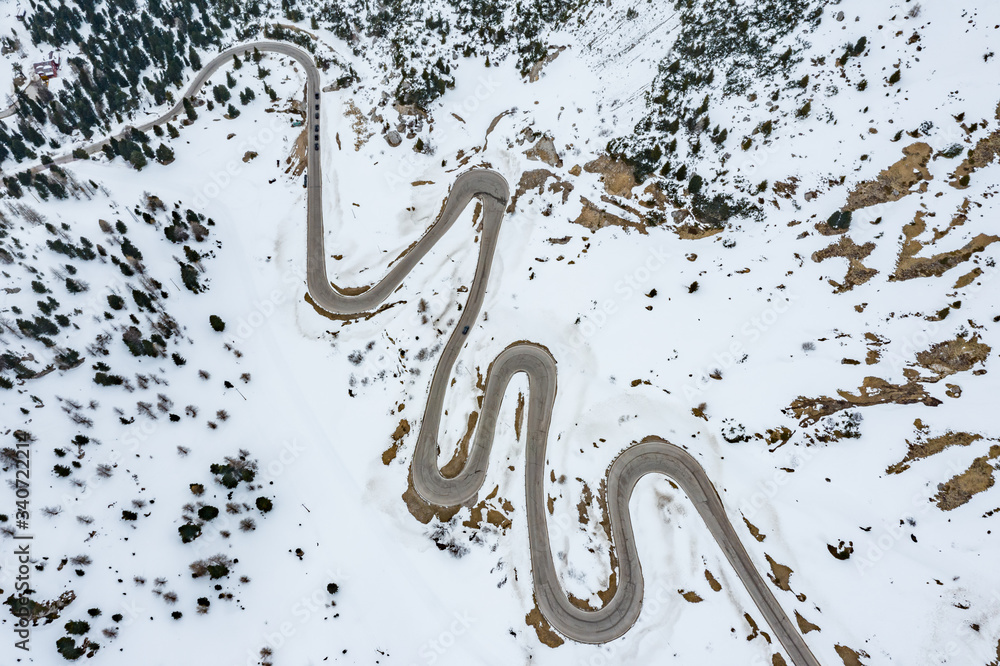 Aerial view of twisting road in the mountains of Italy, is serpentine among the snow-covered hills, is famous place among skiers and fans to understand a known by sports cars, mountains peak