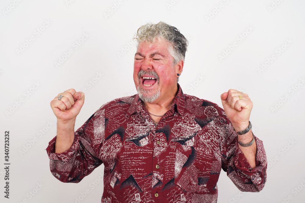 Attractive young man happy and excited expressing winning gesture. Successful and celebrating victory, triumphant, gray background. Attractive young man happy and excited expressing winning gesture. Successful and celebrating victory, triumphant, gray background.