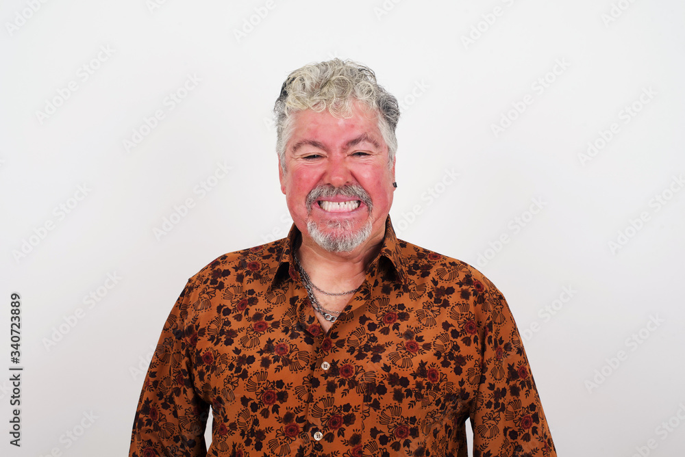 Mad crazy man clenches teeth angrily, being annoyed with coming noise, dressed in fashionable clothes, isolated over gray background. Negative feeling concept. Mad crazy man clenches teeth angrily, being annoyed with coming noise, dressed in fashionable clothes, isolated over gray background. Negative feeling concept.