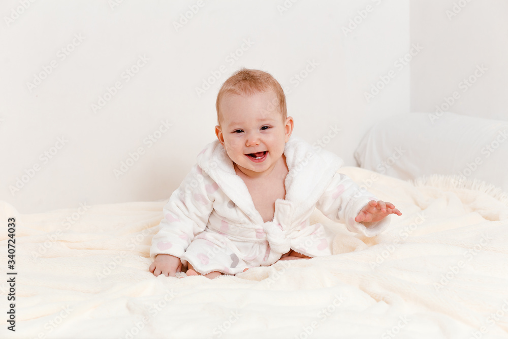 Smiling little girl in a white robe on the bed Smiling little girl in a white robe on the bed