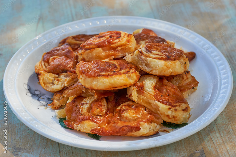 Close up Picture of freshly baked italian style pizza scrolls made from puff pastry and filled with mozzarella cheese and tomato sauce served on the rustic porcelain plate. Snack for childern party.