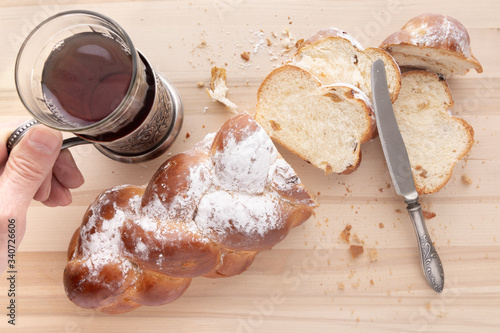 Sliced fresh bread and a vintage knife. Hand holds a glass of tea. Crumbs of bread. Light wooden background. Viewed from above photo