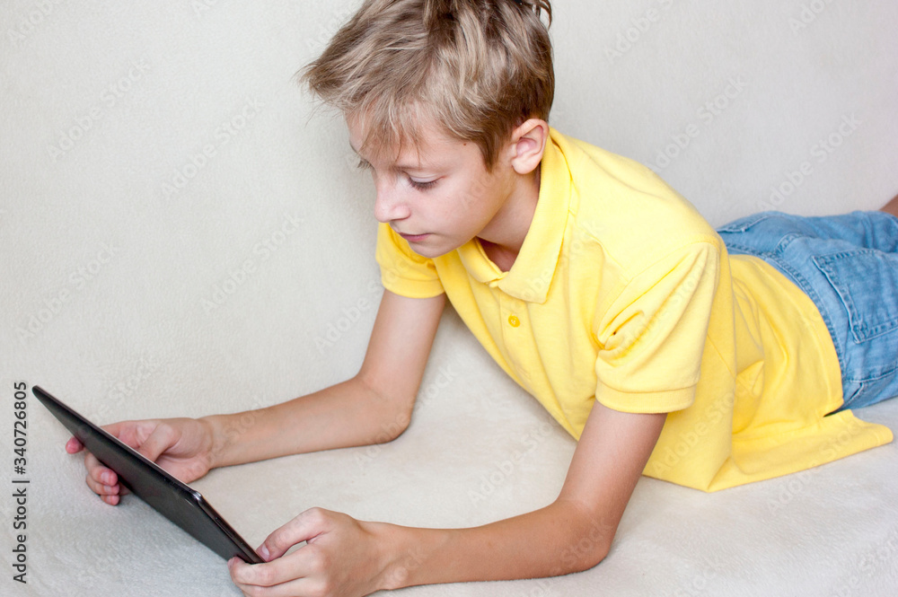 A child with a tablet in his hands. Problems and disadvantages of social networks. Distance learning. Online shopping