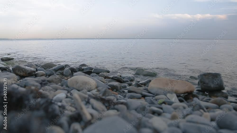 Gentle sea waves roll on the rocky beach in the evening. Gentle sea waves roll on the rocky beach in the evening.