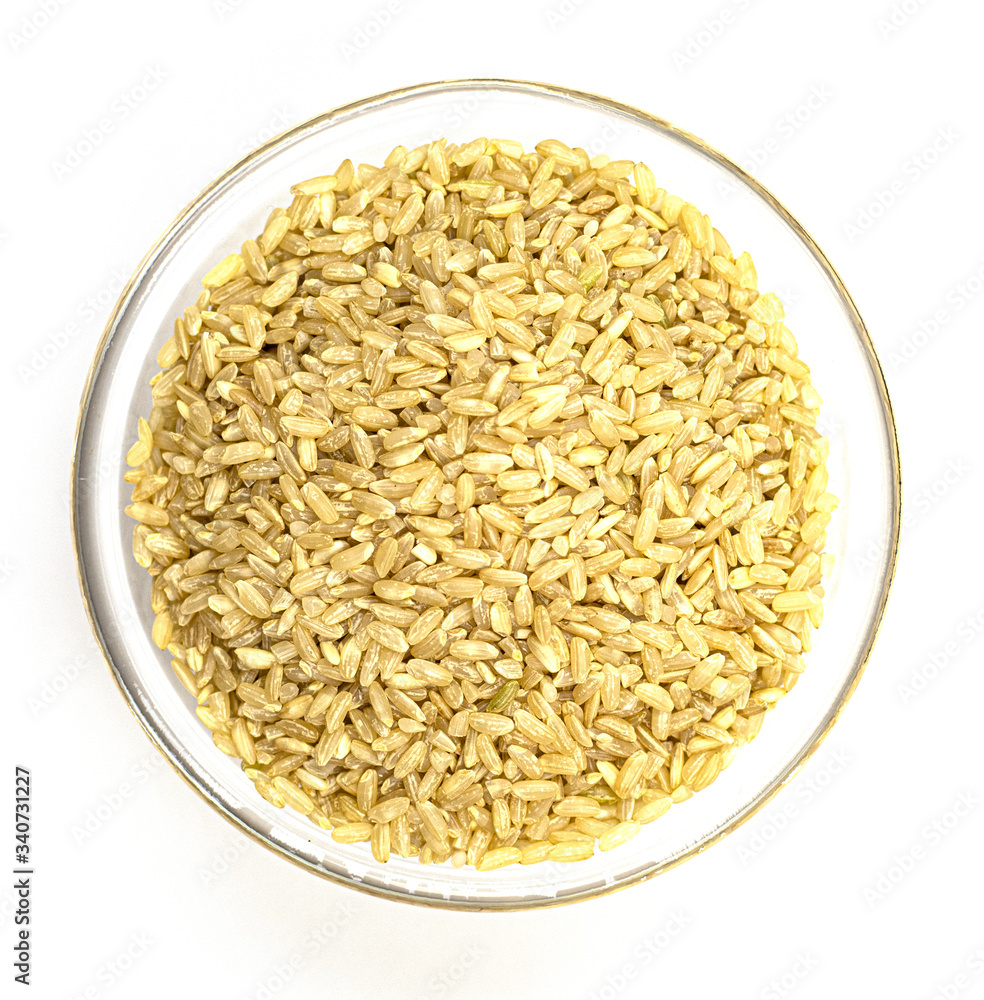 a pile of brown rice in a white bowl, isolated on a white background, top view. unpolished white rice for health. culinary dish for diabetes treatment a pile of brown rice in a white bowl, isolated on a white background, top view. unpolished white rice for health. culinary dish for diabetes treatment