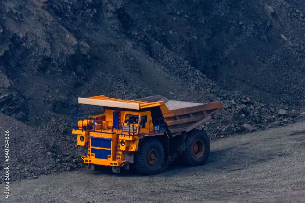 Huge empty dump truck on a gravel road in iron ore quarry Huge empty dump truck on a gravel road in iron ore quarry