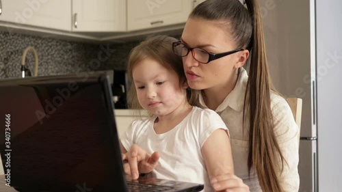 Work remotely. Young bisnesswoman is working on a laptop at home. Little daughter prevents mom from working. Child wants to play. photo