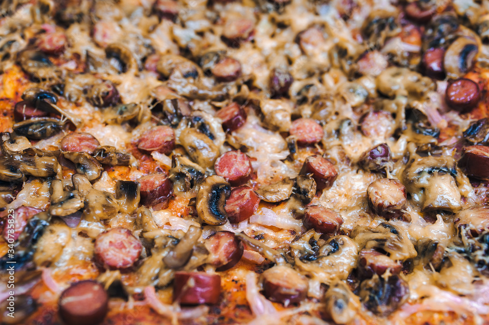 The process of cooking pizza with sausages and mushrooms, onions and tomato paste. Close up, top view. Stage of preparation before sprinkling with cheese. The process of cooking pizza with sausages and mushrooms, onions and tomato paste. Close up, top view. Stage of preparation before sprinkling with cheese.