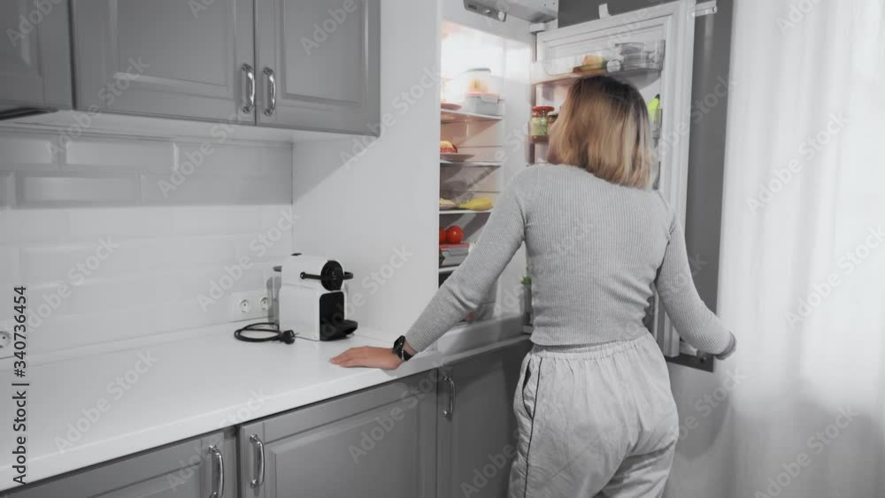 Back view of woman opening the fridge and choosing the best food for her diet Back view of woman opening the fridge and choosing the best food for her diet