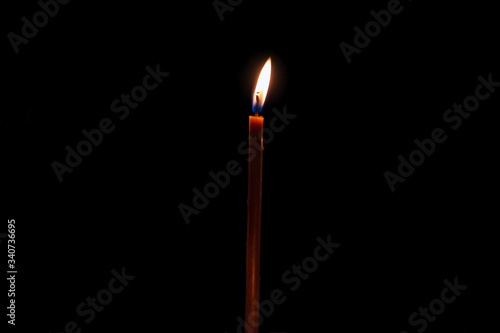 yellow wax candle burning in the dark of night