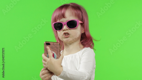 Girl using smartphone. Child emotionally talking on mobile phone, take selfie © Andrii Iemelianenko
