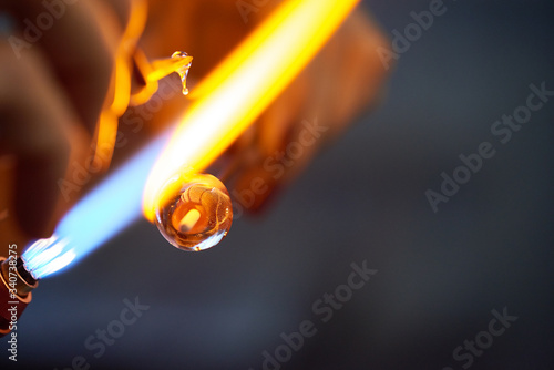 Contemporary artisan burning glass workpiece while holding it close to fire